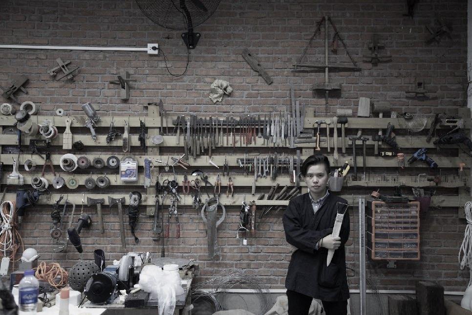 Cao Yun in his studio, standing in front of a wall of sculpting tools